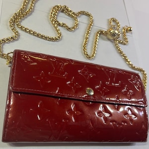 May include: A red leather wallet with a gold chain strap and a Louis Vuitton monogram pattern.