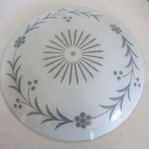 May include: A white glass ceiling light fixture with a frosted finish and a decorative design of gray leaves and berries.