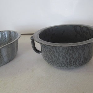 Puede incluir: Dos cuencos de esmalte vintage. Uno es un cuenco redondo con asa y esmalte gris moteado. El otro es un cuenco acanalado con esmalte gris moteado.