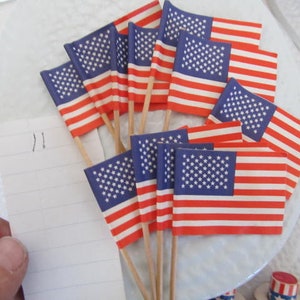 Könnte beinhalten: Eine Sammlung kleiner amerikanischer Fähnchen-Zahnstocher, perfekt zum Dekorieren von Cupcakes oder anderen Leckereien für eine patriotische Feier.