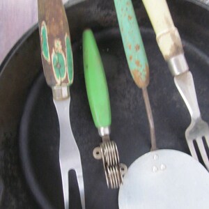 Puede incluir: Cuatro utensilios de cocina vintage con mangos verdes y blancos. Los utensilios incluyen un tenedor, un cortador de masa, un machacador de patatas y un tenedor con una cabeza redonda y plana.