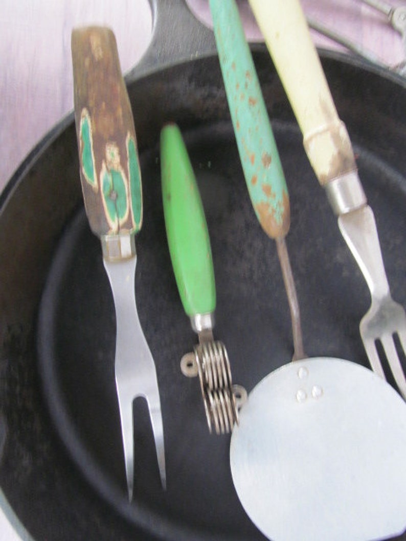 Puede incluir: Cuatro utensilios de cocina vintage con mangos verdes y blancos. Los utensilios incluyen un tenedor, un cortador de masa, un machacador de patatas y un tenedor con una cabeza redonda y plana.