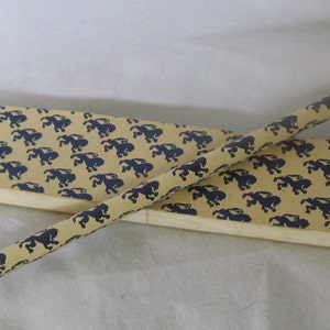 May include: A wooden pencil with a blue and yellow pattern. The pencil is in a box with a similar pattern.