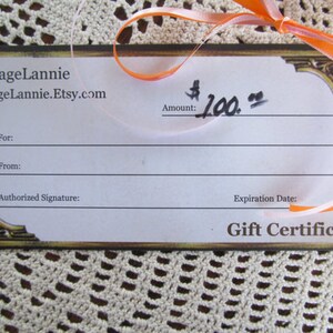 May include: A gift certificate for $100 from ReVintageLannie.Etsy.com. The certificate has a gold border and a ribbon.