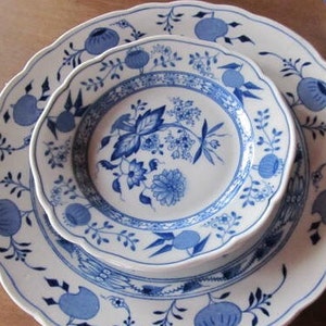 May include: A set of two blue and white porcelain plates with a floral design. The smaller plate is nested inside the larger plate.