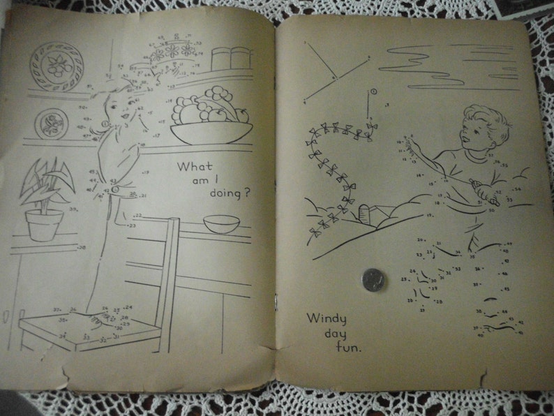 May include: A vintage connect-the-dots activity book with two pages. The left page shows a girl in a kitchen setting with the text "What am I doing?" The right page shows a boy flying a kite with the text "Windy day fun."