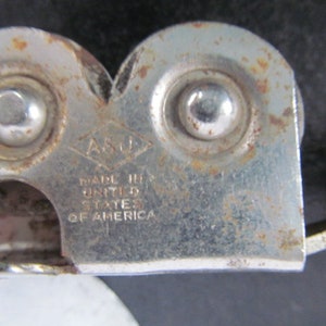 Puede incluir: Un abrelatas de plata con mango negro. El abrelatas tiene dos ruedas y el texto "ASO" y "MADE IN THE UNITED STATES OF AMERICA" est&aacute; impreso en el lateral.