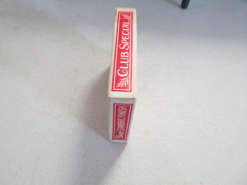 May include: A red and white box of Bee playing cards with the text "Club Special" and "Bee Cambric Finish" printed on the side.
