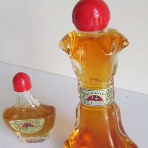 May include: Two glass bottles of perfume, one larger than the other. Both bottles have red caps and are filled with a clear amber liquid. The larger bottle has a label that reads "Irresistible Cologne". The smaller bottle has a label that reads "Irresistible Perfume".