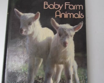 Könnte beinhalten: Ein Buchcover mit dem Titel "Baby Farm Animals" in goldener Schrift auf schwarzem Hintergrund. Zwei weiße Babyziegen sind auf dem Cover abgebildet, eine hinter der anderen.