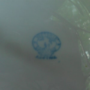 May include: A blue and white porcelain mark with a stylized flower design.