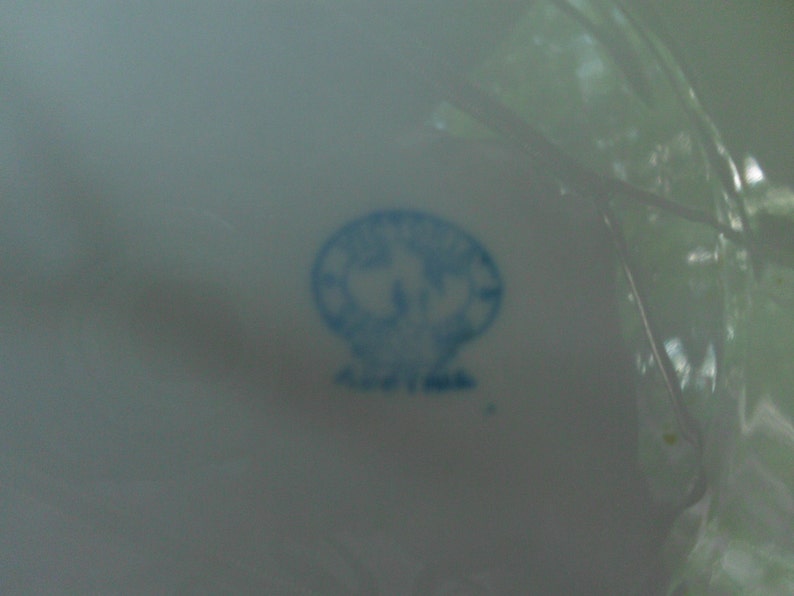 May include: A blue and white porcelain mark with a stylized flower design.