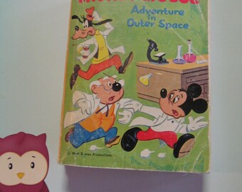 Op de afbeelding: Een vintage Walt Disney's Mickey Mouse stripboek getiteld "Adventure in Outer Space". De cover toont Mickey Mouse, Goofy en een wetenschapper in een laboratorium.