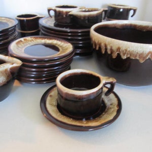 Könnte beinhalten: Ein Set aus braunen und weißen glasierten Keramikgeschirr, bestehend aus einer großen Schüssel, einem Milchkännchen, einem Satz Untertassen und Tassen sowie einem Stapel Speisetellern.
