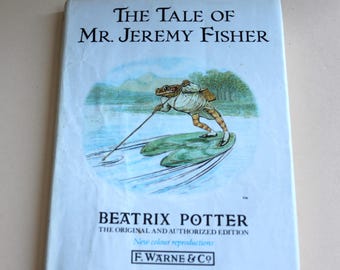 May include: The Tale of Mr. Jeremy Fisher book cover featuring an illustration of a frog in a waistcoat and hat, fishing on a lily pad. The book is by Beatrix Potter and is the original and authorised edition.