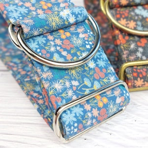 May include: A blue and white floral dog collar with silver hardware. The collar is made of fabric and has a floral pattern.