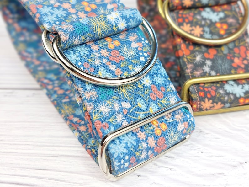 May include: A blue and white floral dog collar with silver hardware. The collar is made of fabric and has a floral pattern.