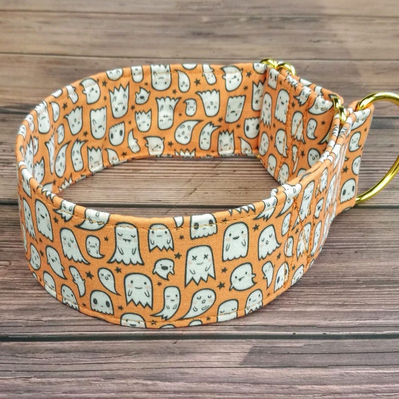 May include: Orange and white dog collar with a pattern of cute ghosts. The collar has a gold metal D-ring.