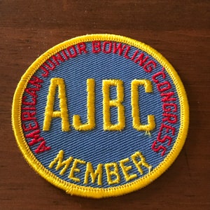 May include: A blue and yellow embroidered patch with the text "American Junior Bowling Congress" and "AJBC Member" in red and yellow thread.