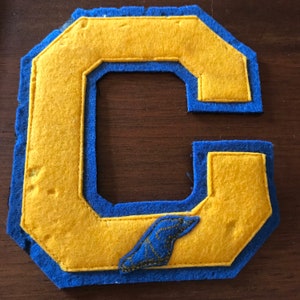 May include: A felt letter C in yellow with blue trim. The letter is sewn with a blue felt bird design in the lower right corner.