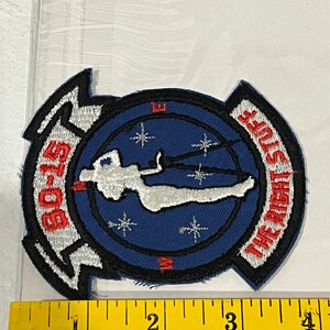 Pu&ograve; includere: Una toppa ricamata blu e bianca con una silhouette bianca di una persona con il paracadute, circondata da stelle bianche. Il testo "GO-15" &egrave; sul lato sinistro della toppa e "THE GREAT STUFF" &egrave; sul lato destro.