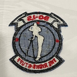 Pu&ograve; includere: Una toppa ricamata blu e bianca con una silhouette bianca di una donna che tiene un fucile. La toppa ha un bordo nero e il testo "808th" e "AIRBORNE" in rosso.