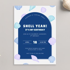 May include: A birthday invitation with a navy blue arch design and the words "SHELL YEAH! IT'S MY BIRTHDAY". The invitation is decorated with watercolor seashells in shades of blue and purple. A white starfish and seashells are on the gray background.