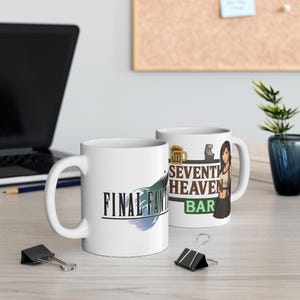 Könnte beinhalten: Zwei weiße Keramikbecher. Ein Becher zeigt das "FINAL FANTASY"-Logo mit einem blau-grünen Federdesign. Der andere Becher zeigt "SEVENTH HEAVEN BAR" mit einer Frauengrafik und einem Bierkrug-Symbol. Beide Becher haben einen weißen Griff.