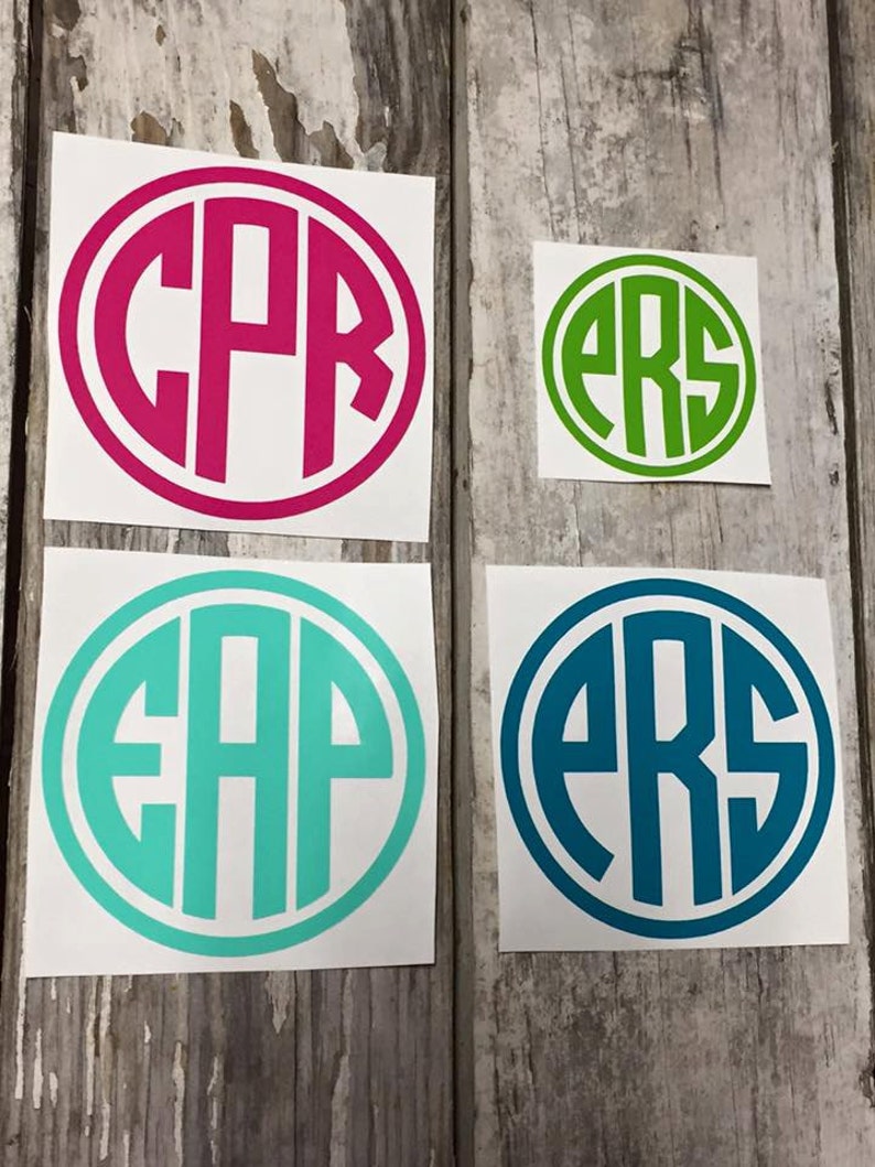 May include: Four round stickers with white backgrounds and black outlines. Each sticker features a different set of three letters in a circle. The letters are in a bold, sans-serif font. The stickers are in the colours pink, green, turquoise, and blue.