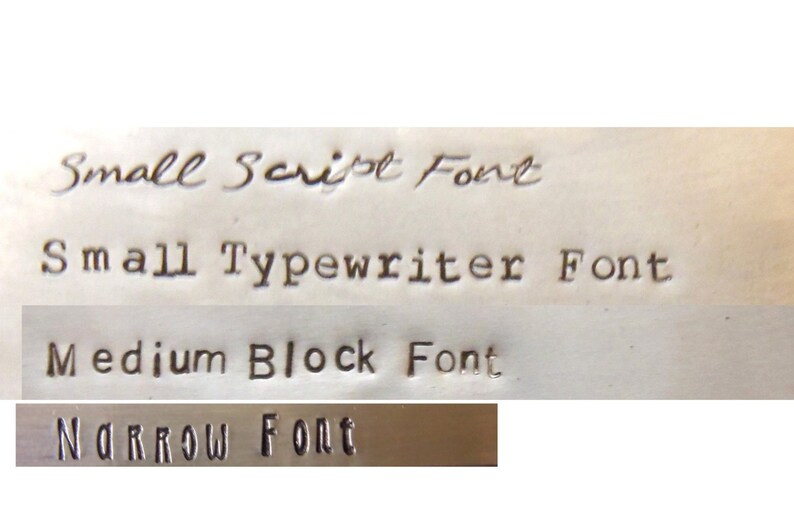 May include: A metal surface displaying four distinct stamped font styles. The text reads Small Script Font, Small Typewriter Font, Medium Block Font, and Narrow Font. Each line demonstrates a different typeface style impressed into the metallic material.