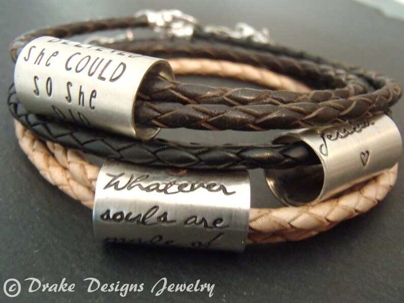 May include: A set of three braided leather bracelets in dark brown and tan, each featuring a cylindrical silver-toned metal bead. The beads are engraved with the phrases "SHE COULD SO SHE DID," "Whatever souls are made of," and a name with a heart.