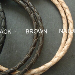 May include: Three braided cords arranged in a circular pattern, labeled as BLACK, BROWN, and NATURAL. Each cord features a consistent woven texture, showcasing distinct color variations in black, dark brown, and a light beige natural tone.