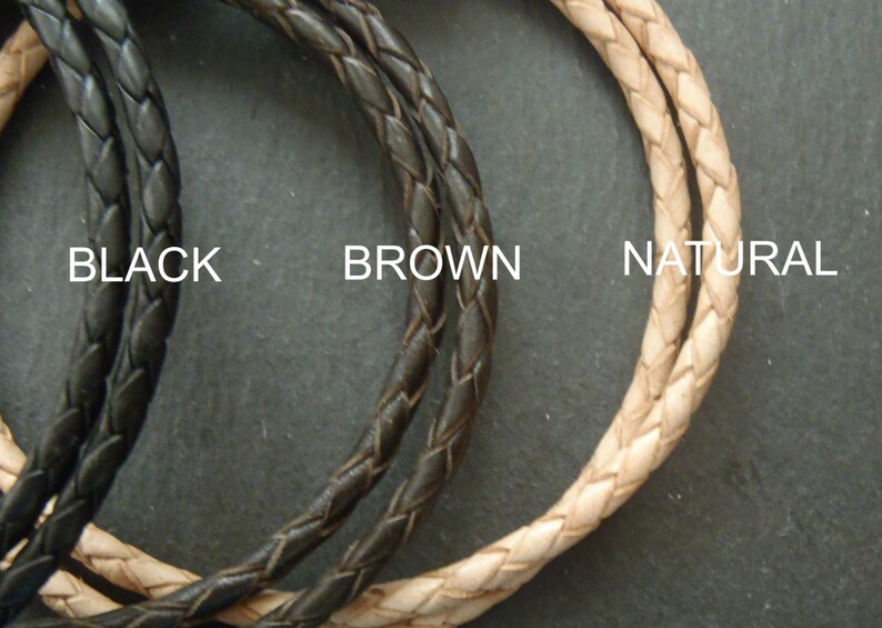 May include: Three braided cords arranged in a circular pattern, labeled as BLACK, BROWN, and NATURAL. Each cord features a consistent woven texture, showcasing distinct color variations in black, dark brown, and a light beige natural tone.