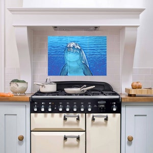 Może przedstawiać: Płytka na ścianę kuchenną w kolorze niebieskim i białym z delfinem pływającym w oceanie. Płytka jest wykonana z ceramiki i ma błyszczące wykończenie.