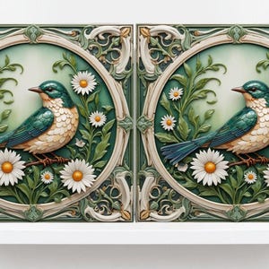 May include: Two ceramic tiles with a green and white floral design featuring a blue bird perched on a branch with white flowers. The tiles have a raised, 3D effect.