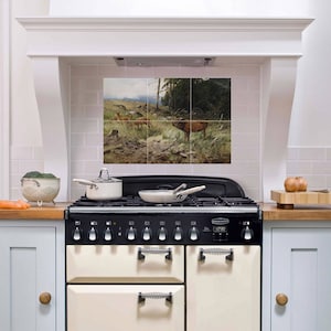 Peut inclure: Une cuisine blanche avec une cuisinière à gaz noire et crème. Le dosseret est carrelé avec une image panoramique d'une forêt avec des cerfs. La cuisinière a une horloge numérique qui affiche 07:30.