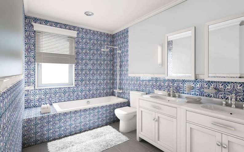 Puede incluir: Un ba&ntilde;o blanco con paredes de azulejos con patrones azules y blancos, una ba&ntilde;era blanca, un tocador blanco con dos lavabos y dos espejos.