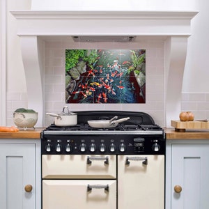 May include: A white kitchen with a black and white range with a decorative tile backsplash featuring a colorful koi pond scene.