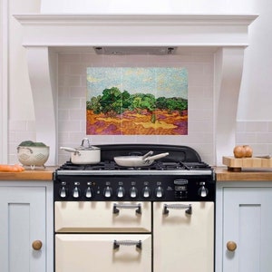 Può includere: Una cucina bianca con una cucina vintage con piano cottura nero e forno color crema. Il paraschizzi è in piastrelle bianche con un dipinto colorato di alberi e un cielo sopra.