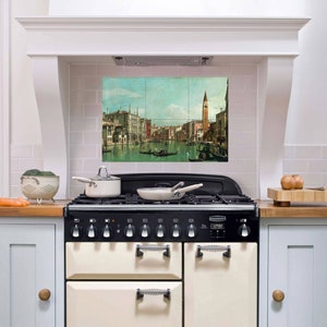 May include: A white kitchen with a vintage-style range and a tiled backsplash featuring a painting of a canal scene in Venice, Italy.