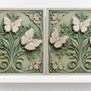May include: Two square ceramic tiles featuring a raised design of stylised green leaves and white butterflies. The tiles are a light green colour with a white border.