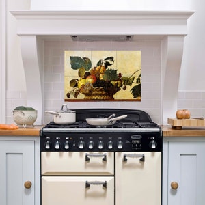 May include: A vintage-style kitchen backsplash with a tiled design featuring a basket of fruit. The fruit includes apples, grapes, pears, and berries. The backsplash is installed above a black and white range with a cream-coloured oven.