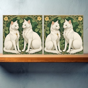 Op de afbeelding: Twee witte katten met groene ogen zitten in een weelderige groene tuinomgeving. De katten kijken elkaar aan en hebben hun staarten om hun lichaam gekruld. De achtergrond is een groen en bruin bloemenpatroon met gele bloemen.