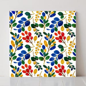 May include: A square canvas print featuring a repeating pattern of colorful botanical elements. The design includes branches with blue, green, and yellow leaves, along with red and yellow berries, set against a white background.