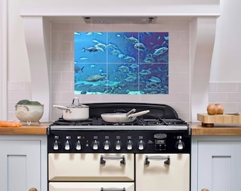 May include: A white kitchen with a black and cream range oven. The backsplash is a tiled mural of a school of fish swimming in blue water.