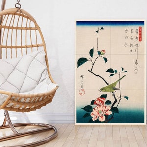 Puede incluir: Una impresión japonesa vintage en madera que representa un pájaro verde posado en una rama con flores de camelia rosas. La impresión tiene un fondo azul y blanco con texto japonés.