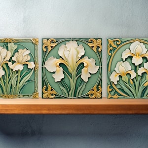 Op de afbeelding: Drie vierkante keramische tegels met een groene achtergrond en gouden rand. Elke tegel heeft een witte irisbloem met een gedetailleerd ontwerp.