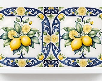 Może przedstawiać: Dwie dekoracyjne płytki ceramiczne z motywem cytryny. Każda płytka ma białe tło z niebieską obwódką i centralny obraz cytryn, liści i plasterków cytryny. Płytki są eksponowane na białej półce.