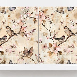 May include: A watercolour illustration of birds, butterflies, and blossoming branches. The design has a vintage aesthetic with soft pink, brown, and beige tones. The image is displayed on a white shelf.