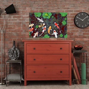 May include: A red dresser with three drawers and black knobs. A framed print of colorful koi fish swimming in a pond with green lily pads is hanging above the dresser.